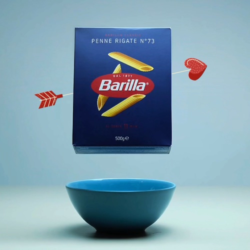Box of Barilla penne pierced by a cupid's arrow, floating above a blue bowl